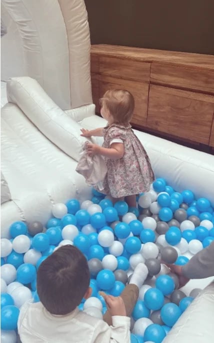 Toddler and young child playing in a ball pit filled with blue and white balls indoors