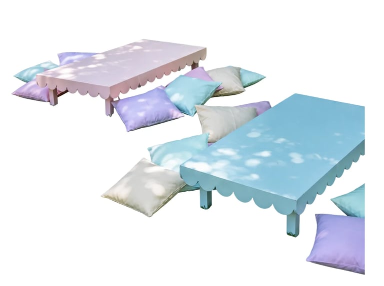 Two pastel-colored beds with scalloped edges and decorative pillows in purple, turquoise, and white