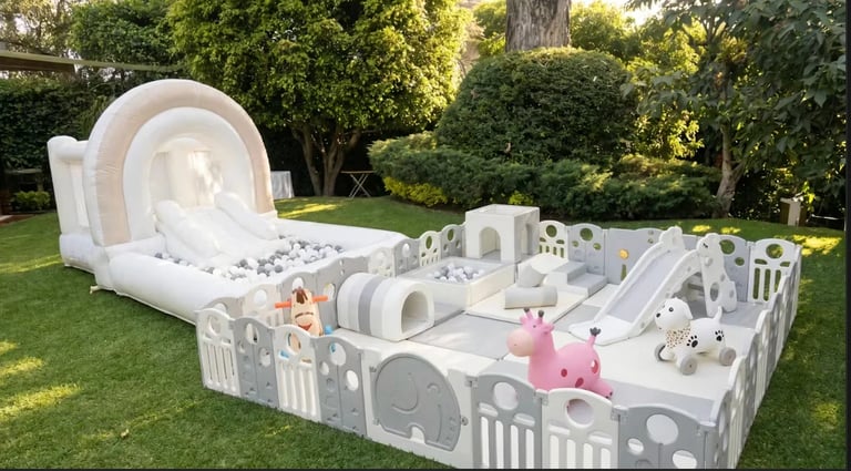 White inflatable play structure with slide, bounce house, and various activities in a grassy backyard setting