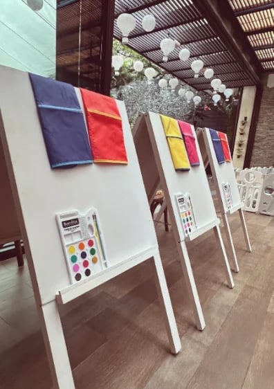 Color palette samples displayed on white boards under a covered outdoor area with hanging lights