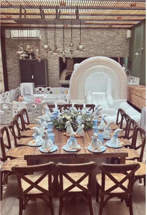 An elegant dining setup with wooden chairs around a table decorated with blue napkins, white plates, and a floral centerpiece in an upscale event space