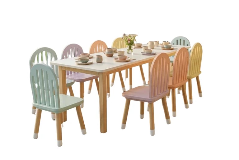 Wooden dining table set with six colorful chairs and place settings on white background